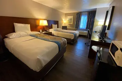 a hotel room with two beds and a desk at Travelodge Inn & Suites by Wyndham Albany in Albany
