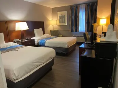 a hotel room with two beds and a desk at Travelodge Inn & Suites by Wyndham Albany in Albany