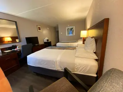 a hotel room with two beds and a desk at Travelodge Inn & Suites by Wyndham Albany in Albany