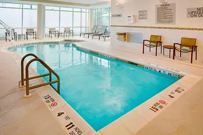 a large swimming pool in a building with tables and chairs at SpringHill Suites by Marriott Carle Place Garden City in Carle Place