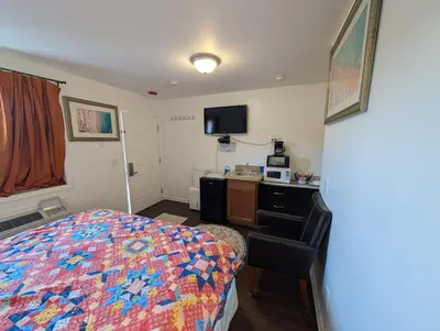 a bedroom with a bed and a desk with a microwave at Apple Inn and Suites Cooperstown Area in Milford