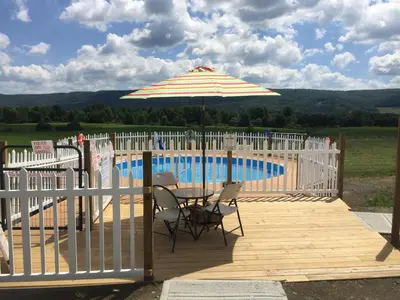 a patio with a table and an umbrella next to a pool at Apple Inn and Suites Cooperstown Area in Milford