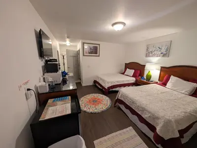 a hotel room with two beds and a television at Apple Inn and Suites Cooperstown Area in Milford