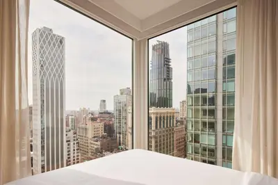 a bedroom with a large window with a view of the city at Arlo NoMad in New York