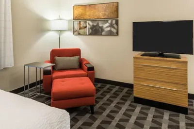 a hotel room with a chair and a flat screen tv at TownePlace Suites by Marriott Latham Albany Airport in Latham