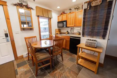 a kitchen with a table and chairs and a kitchen with a sink at Winwood Condominiums by Windham Mountain Club in Windham