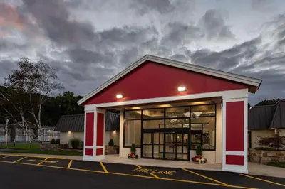 a red and white building on the side of a street at Ramada by Wyndham Hartford North - Bradley Airport in Windsor Locks