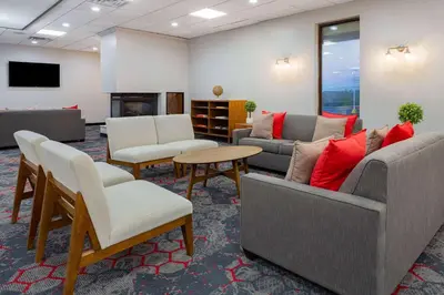 a waiting room with couches and chairs and a table at Ramada by Wyndham Hartford North - Bradley Airport in Windsor Locks
