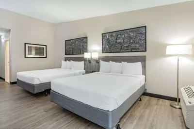 a hotel room with two beds and a desk at Ramada by Wyndham Hartford North - Bradley Airport in Windsor Locks