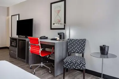 a hotel room with a desk with a computer and two chairs at Ramada by Wyndham Hartford North - Bradley Airport in Windsor Locks