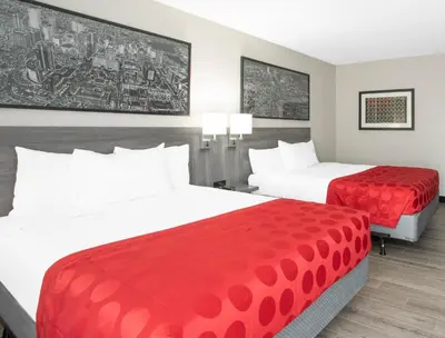 a hotel room with two beds with red sheets at Ramada by Wyndham Hartford North - Bradley Airport in Windsor Locks