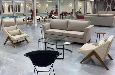 a living room with couches and tables and chairs at Ramada by Wyndham Hartford North - Bradley Airport in Windsor Locks