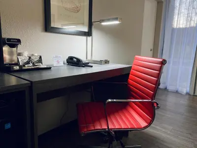 a red chair sitting in front of a desk at Ramada by Wyndham Hartford North - Bradley Airport in Windsor Locks
