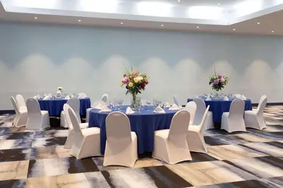 a conference room with blue tables and white chairs at Ramada by Wyndham Hartford North - Bradley Airport in Windsor Locks