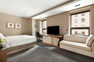 a hotel room with a bed and a couch and a television at Hyatt Grand Central New York in New York