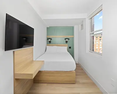 a bedroom with a bed and a flat screen tv at Riverside Tower Hotel in New York