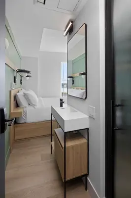 a bathroom with a sink and a mirror and a bed at Riverside Tower Hotel in New York