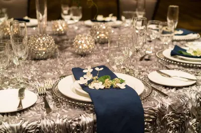 a long table with plates and glasses and blue napkins at The Saratoga Hilton in Saratoga Springs