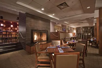 a restaurant with tables and chairs and a fireplace at The Saratoga Hilton in Saratoga Springs