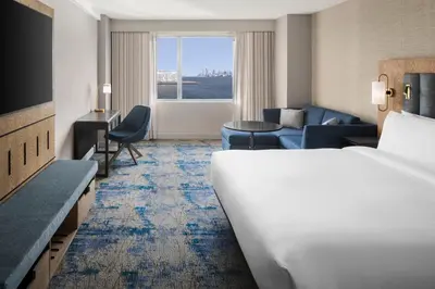 a hotel room with a bed and a living room at Hyatt Regency Jersey City on the Hudson in Jersey City