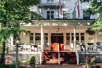 a white house with a front porch with an american flag at The Red Lion Inn in Stockbridge