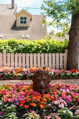 a statue in a bed of flowers in front of a fence at The Red Lion Inn in Stockbridge