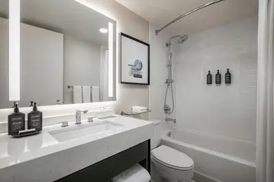 a white bathroom with a sink and a toilet at Sheraton LaGuardia East Hotel in Queens