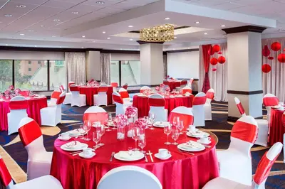 a banquet hall with red and white tables and chairs at Sheraton LaGuardia East Hotel in Queens