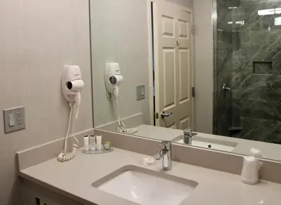 a bathroom with a sink and a large mirror at Marco LaGuardia Hotel & Suites in Queens