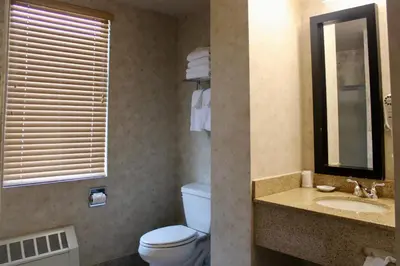 a bathroom with a toilet and a sink and a mirror at Marco LaGuardia Hotel & Suites in Queens