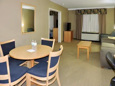 a living room with a table and chairs and a couch at Marco LaGuardia Hotel & Suites in Queens