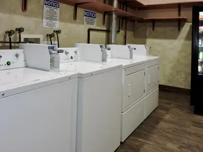 a row of white washing machines in a room at Marco LaGuardia Hotel & Suites in Queens