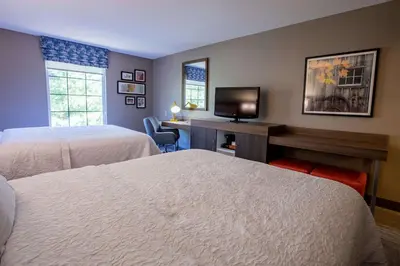 a hotel room with two beds and a desk with a television at Hampton Inn Hadley-Amherst Area in Hadley