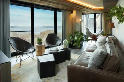 a living room with a couch and chairs and windows at 1 Hotel Brooklyn Bridge in Brooklyn