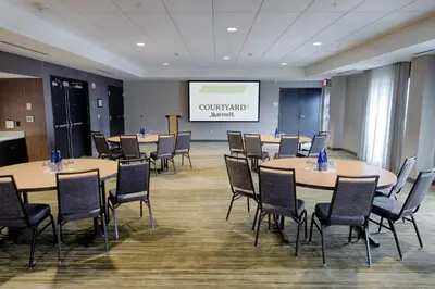 a conference room with tables and chairs and a screen at Courtyard by Marriott Albany Clifton Park in Clifton Park