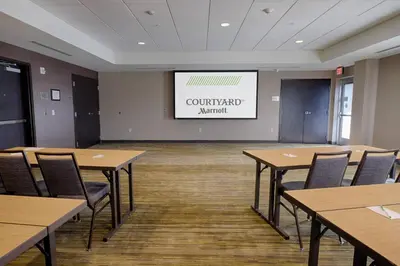 a conference room with tables and chairs and a screen at Courtyard by Marriott Albany Clifton Park in Clifton Park