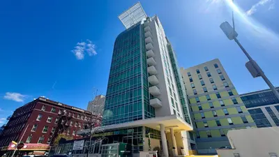 a tall glass building on a city street at LIC Manhattan View Hotel in Queens