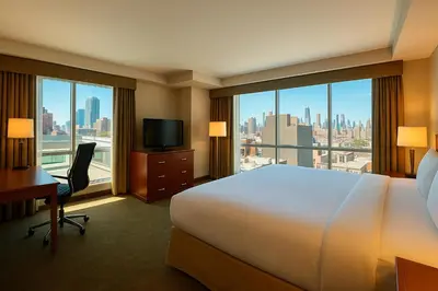 a hotel room with a bed and a desk and windows at LIC Manhattan View Hotel in Queens