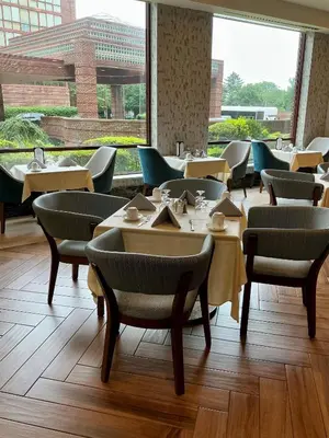 a restaurant with tables and chairs and a large window at DoubleTree by Hilton New York-LaGuardia in Queens