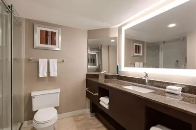 a bathroom with a toilet and a sink and a mirror at DoubleTree by Hilton New York-LaGuardia in Queens