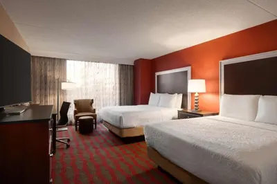 a hotel room with two beds and a desk at DoubleTree by Hilton New York-LaGuardia in Queens