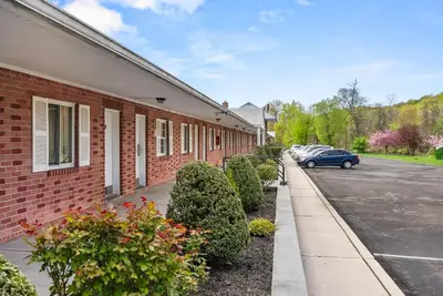 a brick building with cars parked in a parking lot at Ardsley Acres Hotel Court in Ardsley