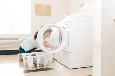 a woman loading a washing machine in a kitchen at Candlewood Suites Secaucus by IHG in Secaucus