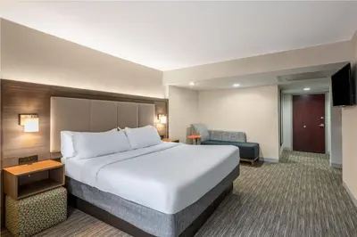 a hotel room with a large bed and a chair at Country Inn & Suites by Radisson, Downtown Albany New York in Albany