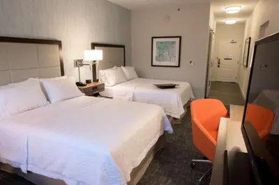 a hotel room with two beds and a chair at Hampton Inn Albany-Western Ave/University Area, NY in Albany