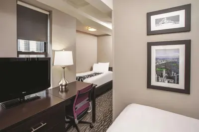 a hotel room with a bedroom with a bed and a television at La Quinta by Wyndham New York City Central Park in New York