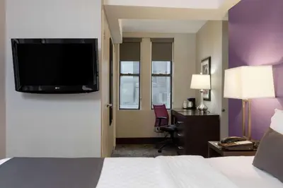 a hotel room with a bed and a flat screen tv at La Quinta by Wyndham New York City Central Park in New York