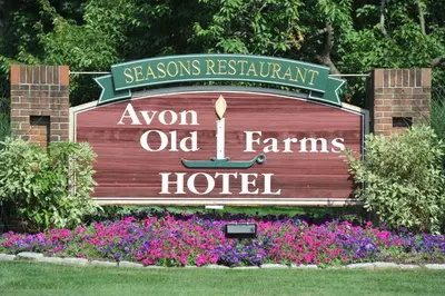 a sign for an olden old farms hotel with flowers at Avon Old Farms Hotel in Avon