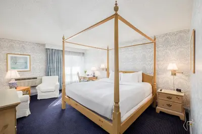 a bedroom with a canopy bed with a white bedspread at The Farmington Inn and Suites in Farmington