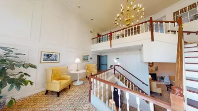 a living room with a staircase and a chair at The Farmington Inn and Suites in Farmington